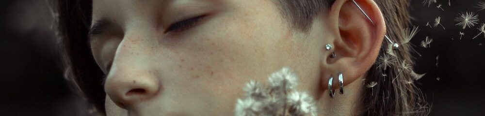 Woman with tragus piercing and other cartilage piercings holding a flower