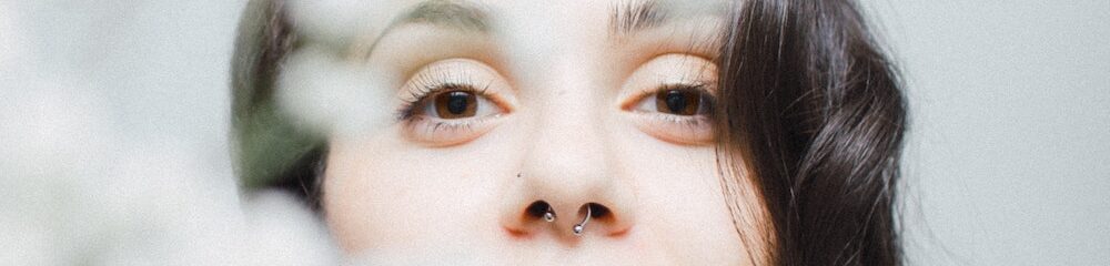 Woman with septum piercing and blurred flowers in foreground