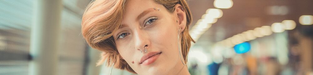 Woman with nostril, eyebrow, and multiple ear piercings